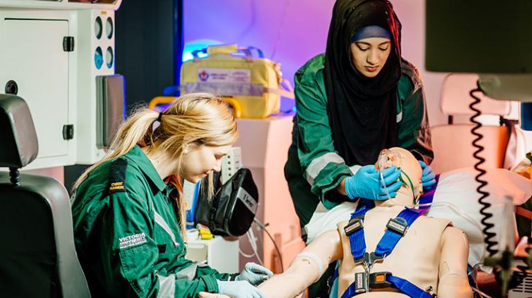 Two paramedics tending to a manikin