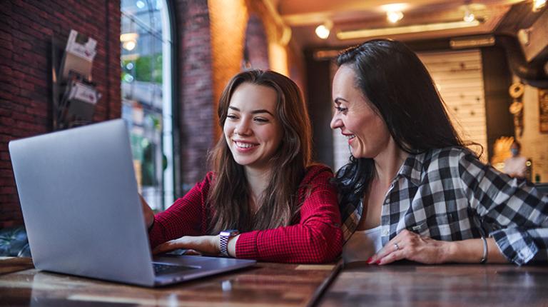  A parent and teenager looking at a laptop and planning their Open Day.
