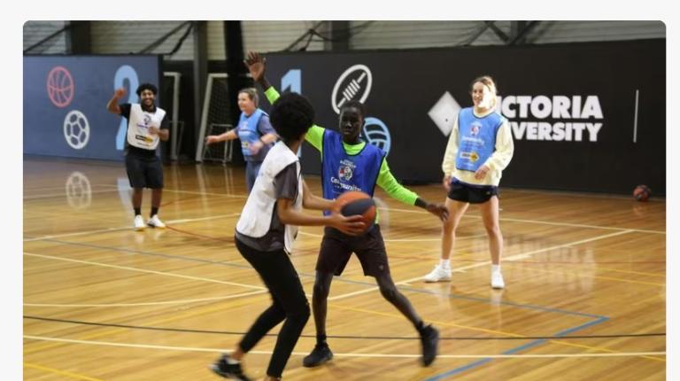 A multicultural group of teenage boys play basketball with VU students
