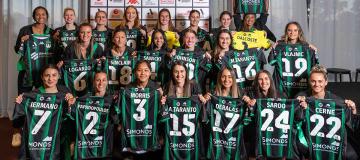 Women's football team proudly hold up team jerseys