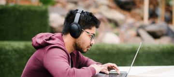 Student using a laptop outdoors on campus 