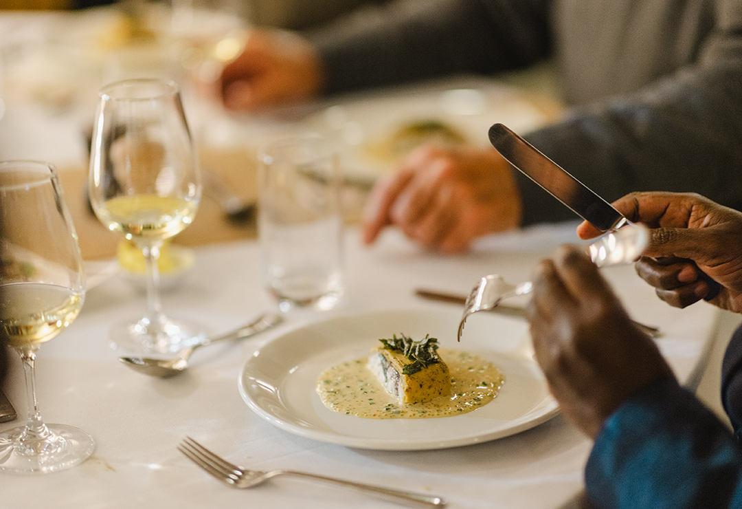 A formal, sophisticated dinner with glass of white wine served on a table with white cloth
